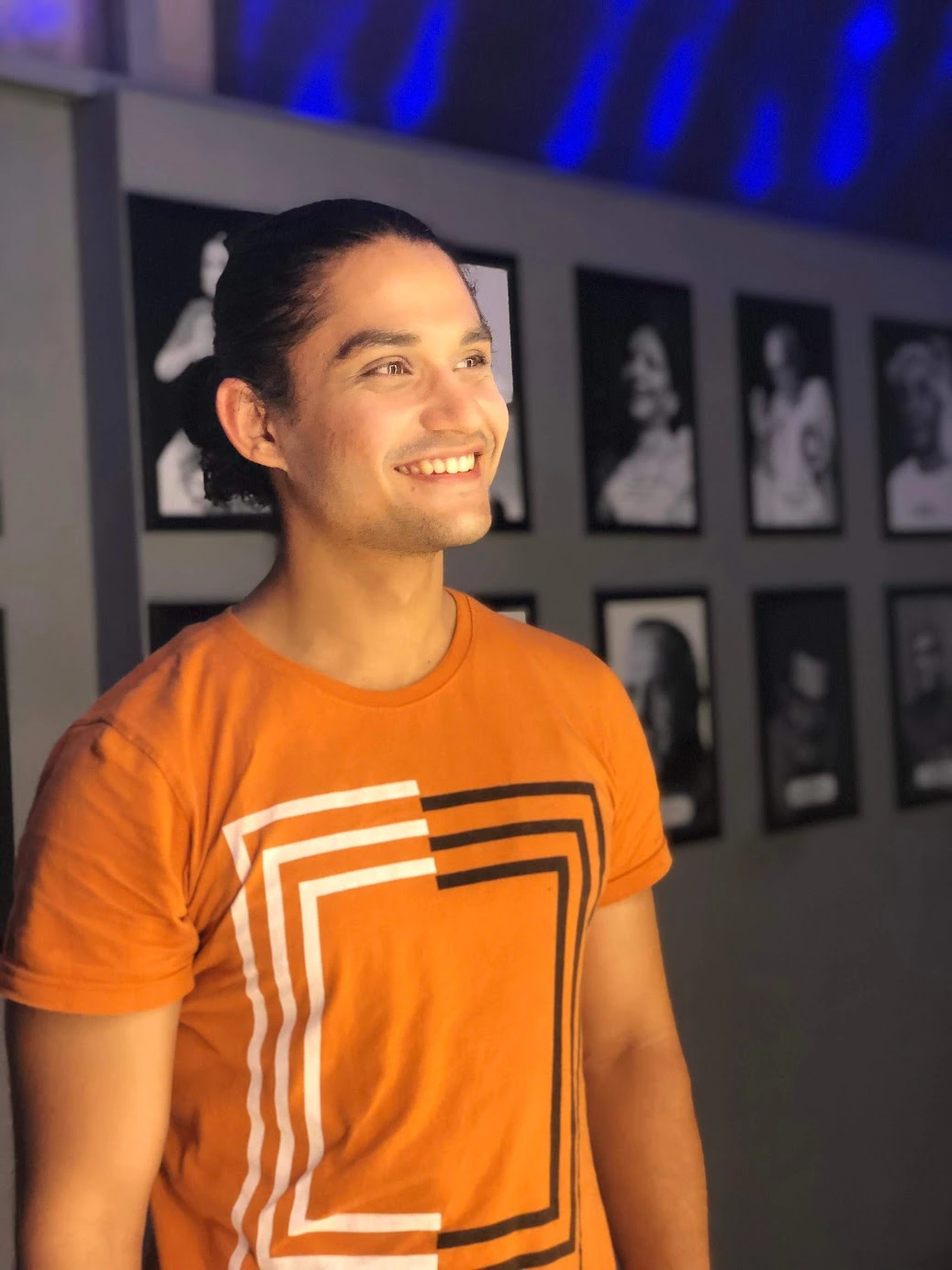 I smile and look to the side in an orange T-shirt